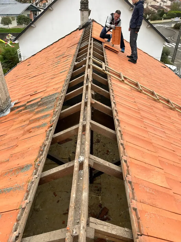Toiture ouverte sur toute sa longueur, charpente à nu, deux compagnons au travail